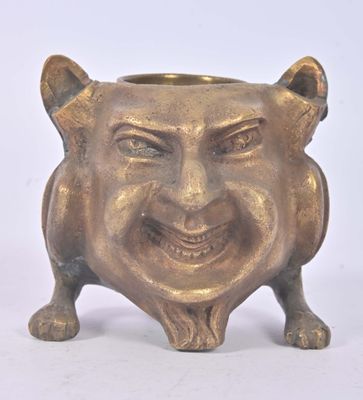 un petit pot en or orné d'un visage souriant