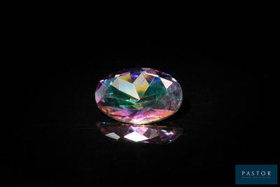 un gros plan d'un diamant aux couleurs de l'arc-en-ciel posé sur une surface noire