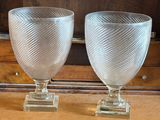 une paire de verres à pied en verre transparent posés sur une commode en bois