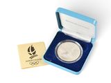 une pièce d'argent olympique dans un coffret bleu contenant une médaille d'or