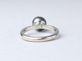 a close up of a silver ring with a black pearl on it