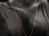 une femme vêtue d'une robe noire et portant un collier à chaîne dorée