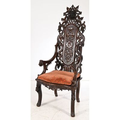 an ornately carved chair with orange upholstered seat