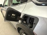 a silver car with an electric charger attached to it ' s side