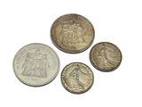 four different types of silver coins on a white surface