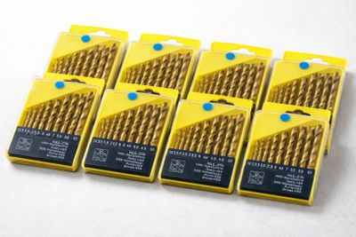 six paquets de forets « Gold Drill » dans des boîtes jaunes, posés sur une surface blanche