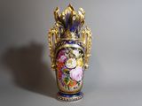 un vase avec des fleurs peintes dessus, posé sur une table
