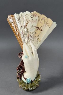a white hand holding a fan on a table