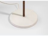 a close up of a lamp on a white surface with a wooden pole