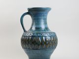 un vase bleu muni d'une anse, sur fond blanc