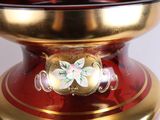 a red and gold vase with a flower on it