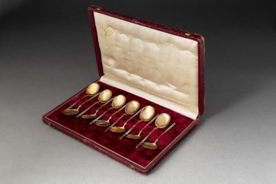 six cuillères dans un étui rouge posé sur une table