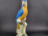 a figurine of a blue and yellow parrot on a branch