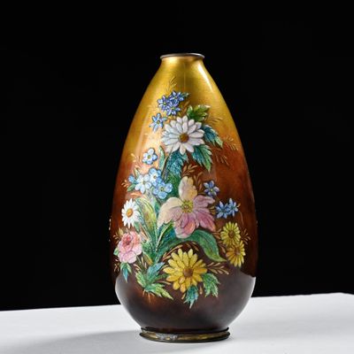 a brown vase with flowers painted on it on a table