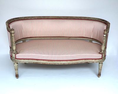 un canapé à l'ancienne dont l'assise est recouverte d'un tissu rayé rouge et blanc