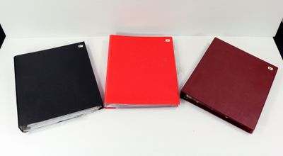 trois cahiers rouges et noirs posés sur une table blanche