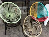 three colorful chairs sitting in a room with boxes of boxes in the background