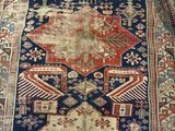 an old persian rug with a blue and red design on a wooden floor