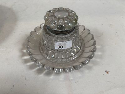 un bougeoir en verre posé sur une table, sur lequel est collée une étiquette