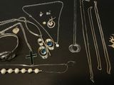 a lot of silver jewelry on a black table