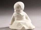 a white figurine of a child sitting on a white surface