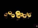 a group of yellow sapphires on a black surface