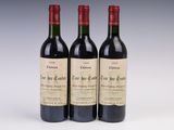 three bottles of red wine sitting next to each other on a table