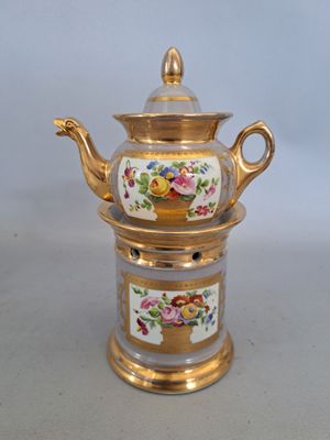 une théière dorée et blanche ornée de fleurs