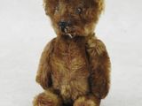 a brown teddy bear sitting on a white surface