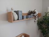 a wooden shelf that has some books and a plant on it