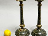 pair of black and gold candlesticks next to a lemon on a white background