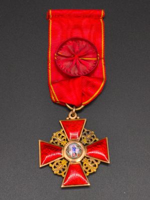 a close up of a red and gold medal with a cross on it