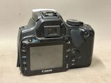 a canon camera sitting on a table with a white wall in the background