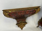 pair of ornate gold and red painted shelf brackets on a white background