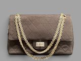 brown quilted purse with gold chain strap on grey background