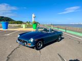 a blue convertible car parked in a parking lot next to the water