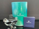 une petite figurine posée à côté d'un coffret de parfum