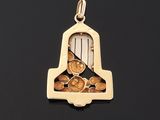 a gold pendant with a picture of a man in a chair