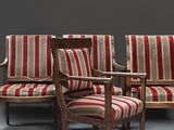trois chaises avec des coussins rembourrés à rayures et un accoudoir en bois