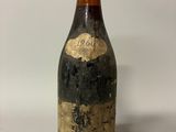 an old bottle of wine sitting on top of a white table