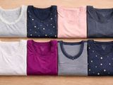 six paires de t-shirts disposées en rangée sur une surface en bois