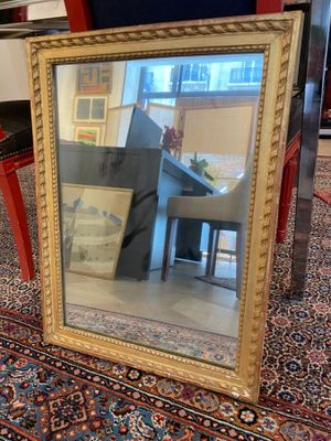 a large mirror sitting on the floor in front of a piano