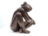 a statue of a man sitting on a white surface