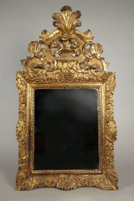 un miroir au cadre doré ouvragé, avec un verre noir au centre