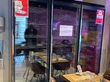 des tables et des chaises dans un restaurant, avec un réfrigérateur en arrière-plan