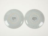 pair of blue and white plates with gold rims on a white surface