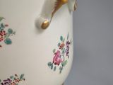 a white vase with a gold handle and flowers on it