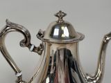a silver tea pot with a handle on a table