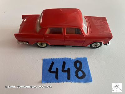 une petite voiture rouge posée à côté d'une feuille de papier bleue