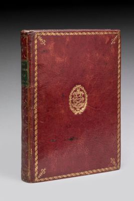 un vieux livre rouge aux tranches dorées, orné d'un médaillon doré sur la couverture